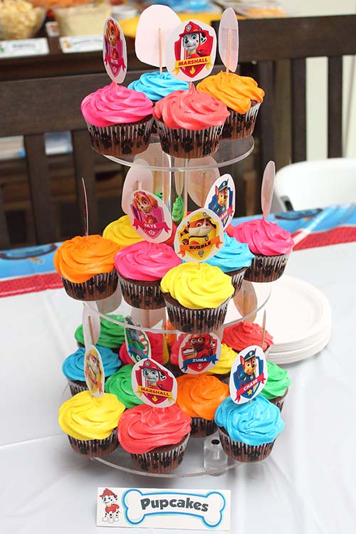 a three-tier cupcake stand full of Paw Patrol-themed cupcakes