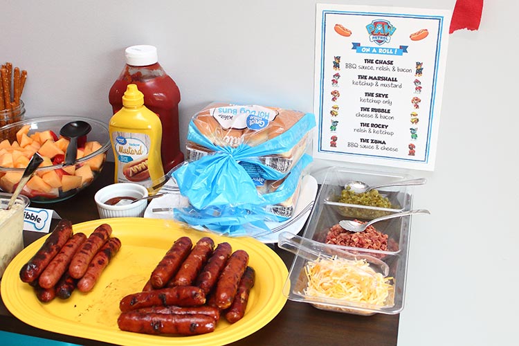 a platter of grilled hot dogs with buns and toppings