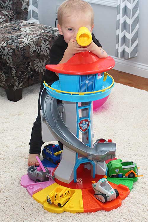 a little boy standing behind a large Paw Patrol Lookout Tower toy