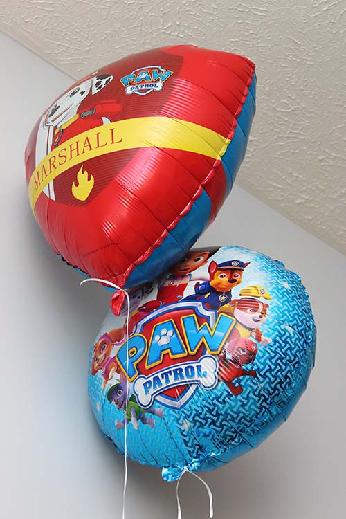 two Paw Patrol mylar balloons floating, one featuring Marshall