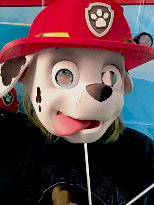 a woman holding a photo prop of Marshall from Paw Patrol up to her face