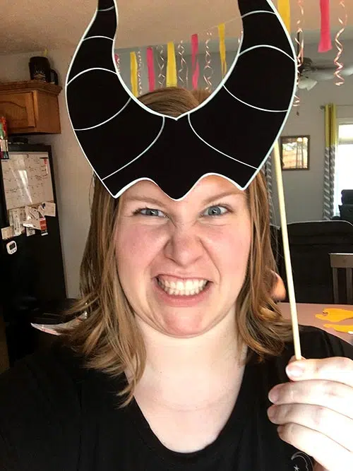 a woman snarling while holding a Maleficent horn photo prop on the top of her head