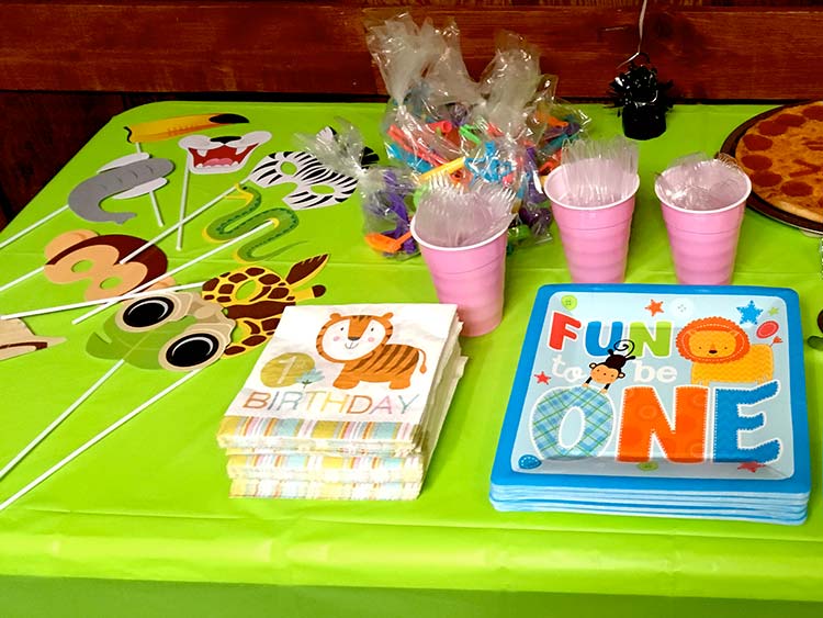 jungle photo props, bags of simple party favors, and napkins and plates with a 