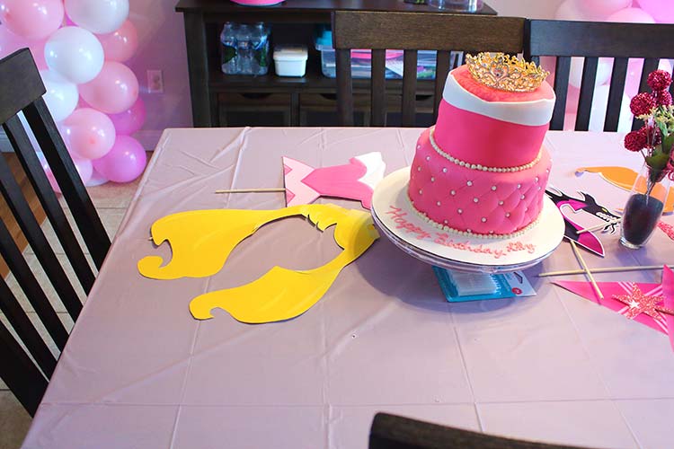 lavender table with a two-tier Sleeping Beauty dress cake and photo props