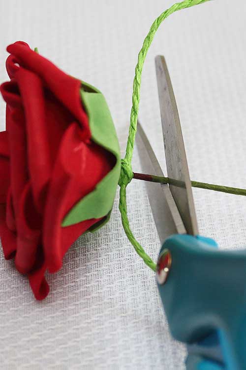 scissors in position to cut off most of a silk rose wire stem