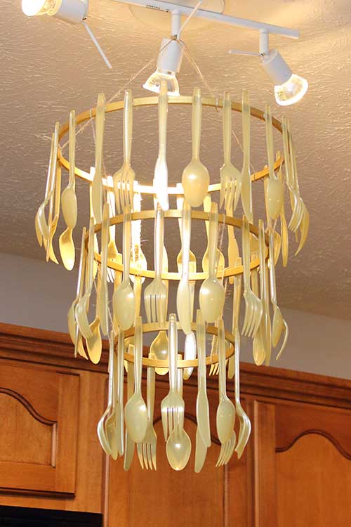 a homemade gold cutlery chandelier hanging from track lights