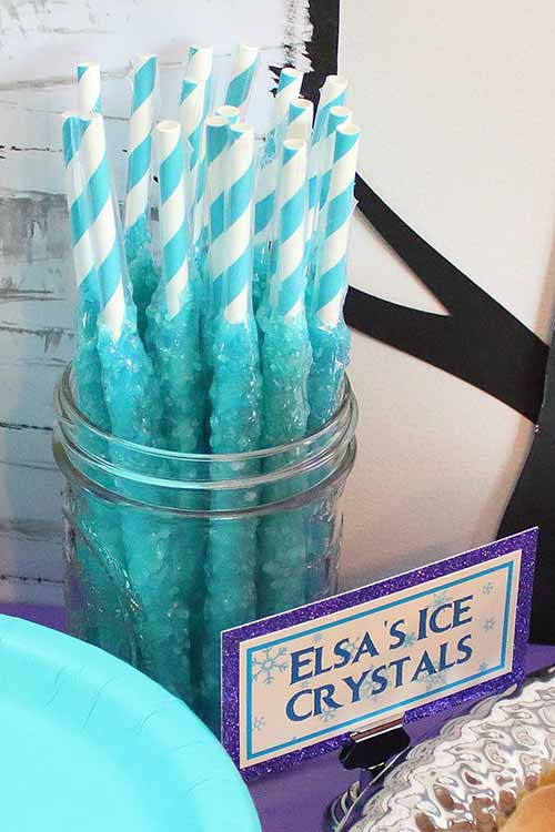 a mason jar full of icy blue rock candy sticks labeled "Elsa's Ice Crystals"