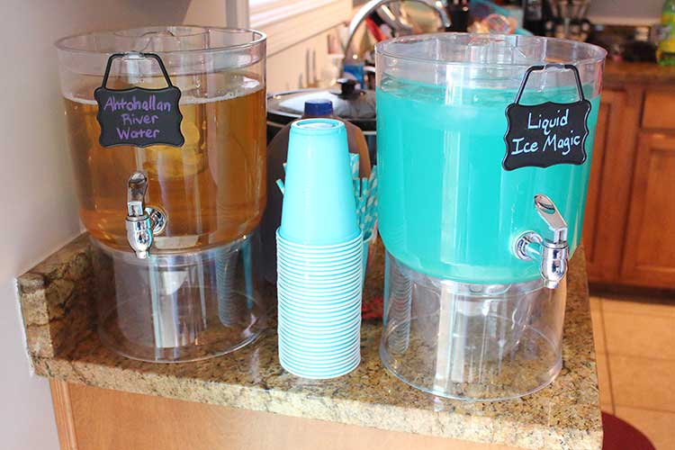 two drink dispensers, one with a brown liquid labeled "Ahtohallan River Water" and the other with a teal-blue liquid labeled "Liquid Ice Magic"