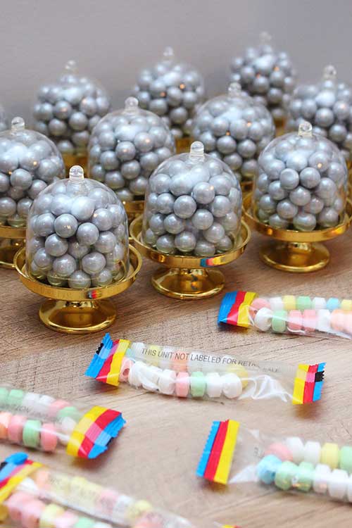 party favors including mini covered cake stands filled with grey sixlets and individually wrapped candy bracelets