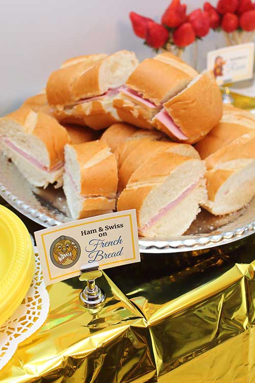 a platter of sandwiches with a food card labeled "Ham & Swiss on French Bread" featuring the Beast