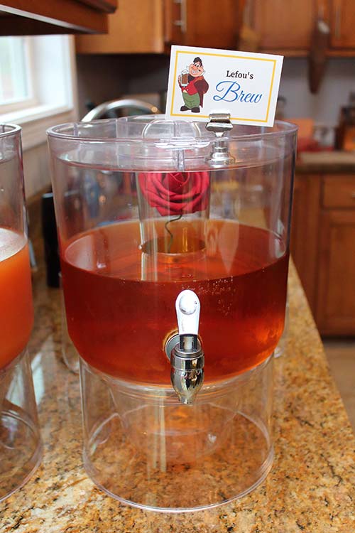 a deep red-brown drink in a dispenser with a rose in the ice chamber labeled "Lefou's Brew"
