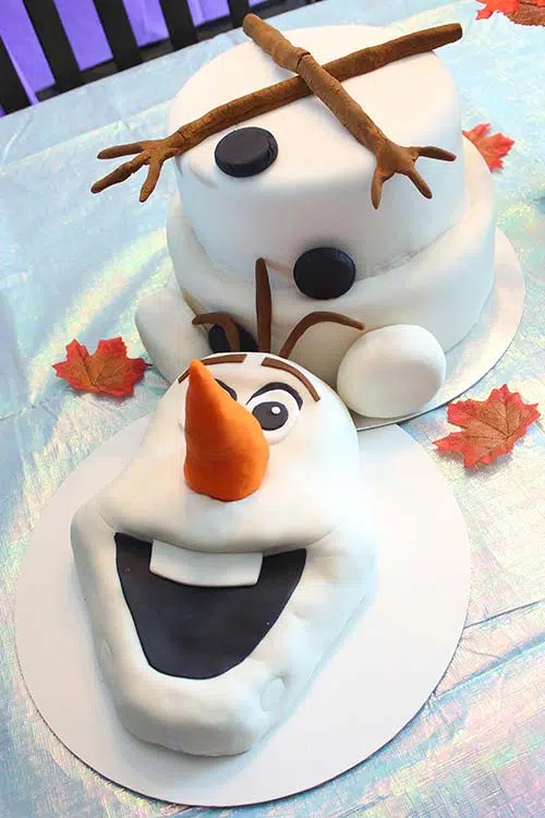 a Frozen birthday cake of Olaf with his head detached and his branch arms lying on top of his torso