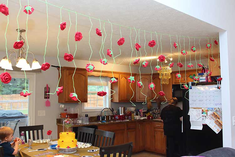 a red rose garland hanging between two rooms during a Beauty and the Beast birthday party