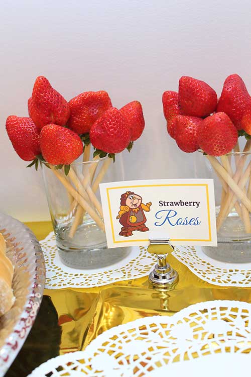 strawberries on candy apple sticks with a food card labeled "Strawberry Roses" featuring Cogsworth