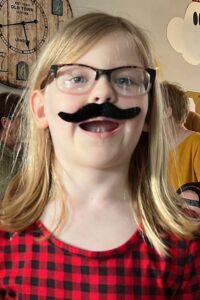 young girl wearing a fake mustache