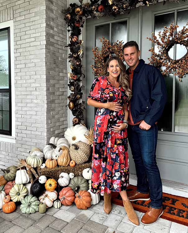 couple posing outside their home decorated for fall