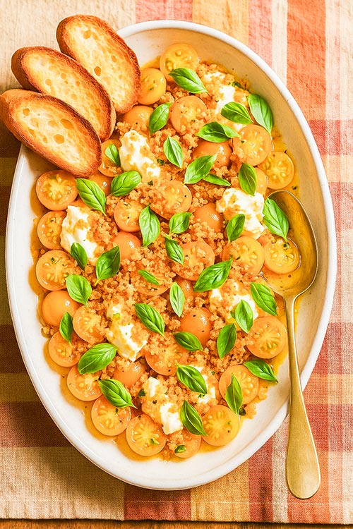 an oval plate full of tomato caprese and burrata