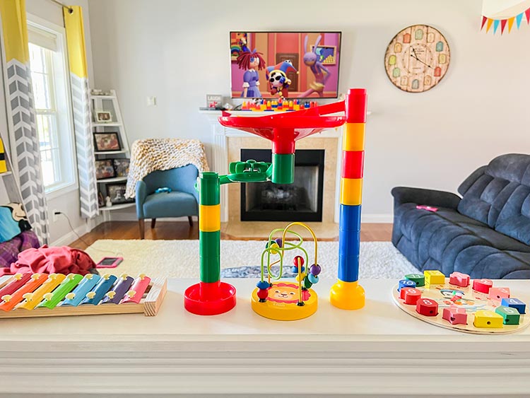half-wall covered in rainbow themed baby toys with TADC on TV