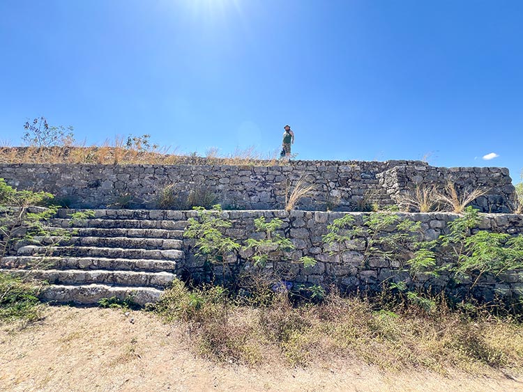 Person standing atop stone bleachers at Dzibilchaltun ruins