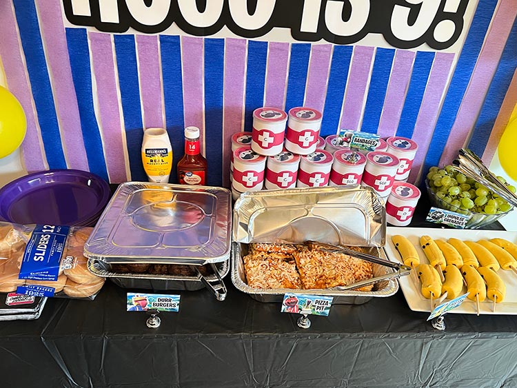 Fortnite themed party food table with burgers pizza and snacks