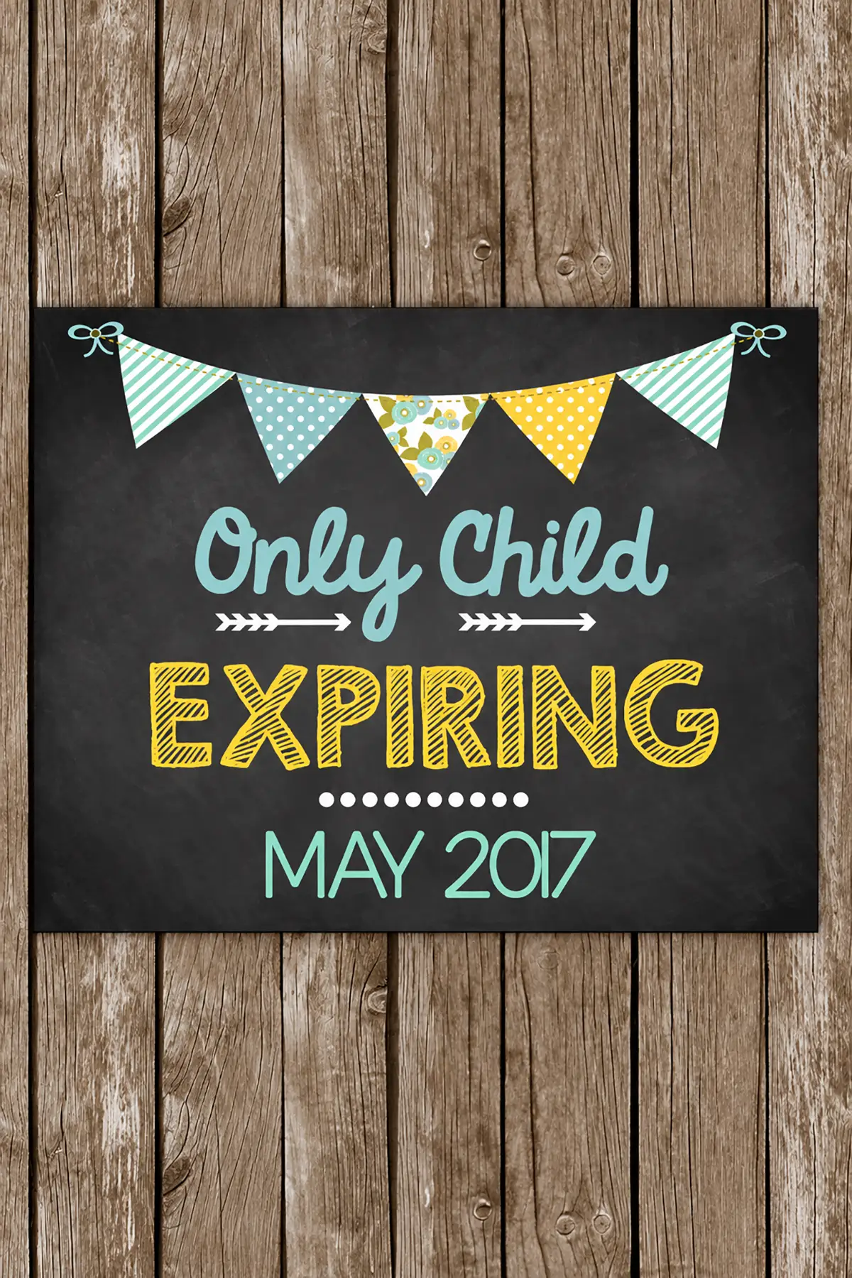 Rustic pregnancy announcement sign reading "Only Child Expiring May 2017" with colorful bunting on a wooden background.