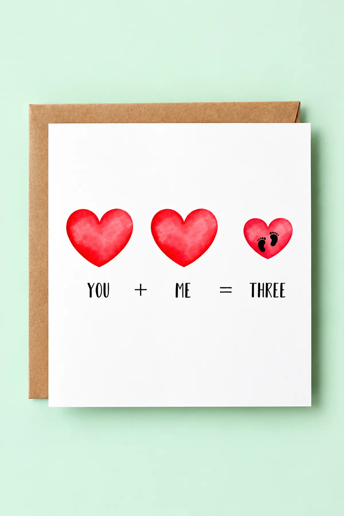 Pregnancy announcement card featuring three red hearts, baby footprints, and the message "You + Me = Three" on a mint background.